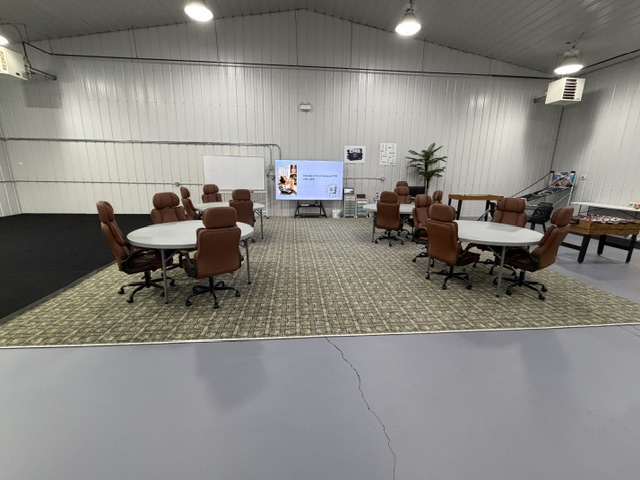 Wide view of Sharalife training classroom with tables, presentation screen, and equipment cart